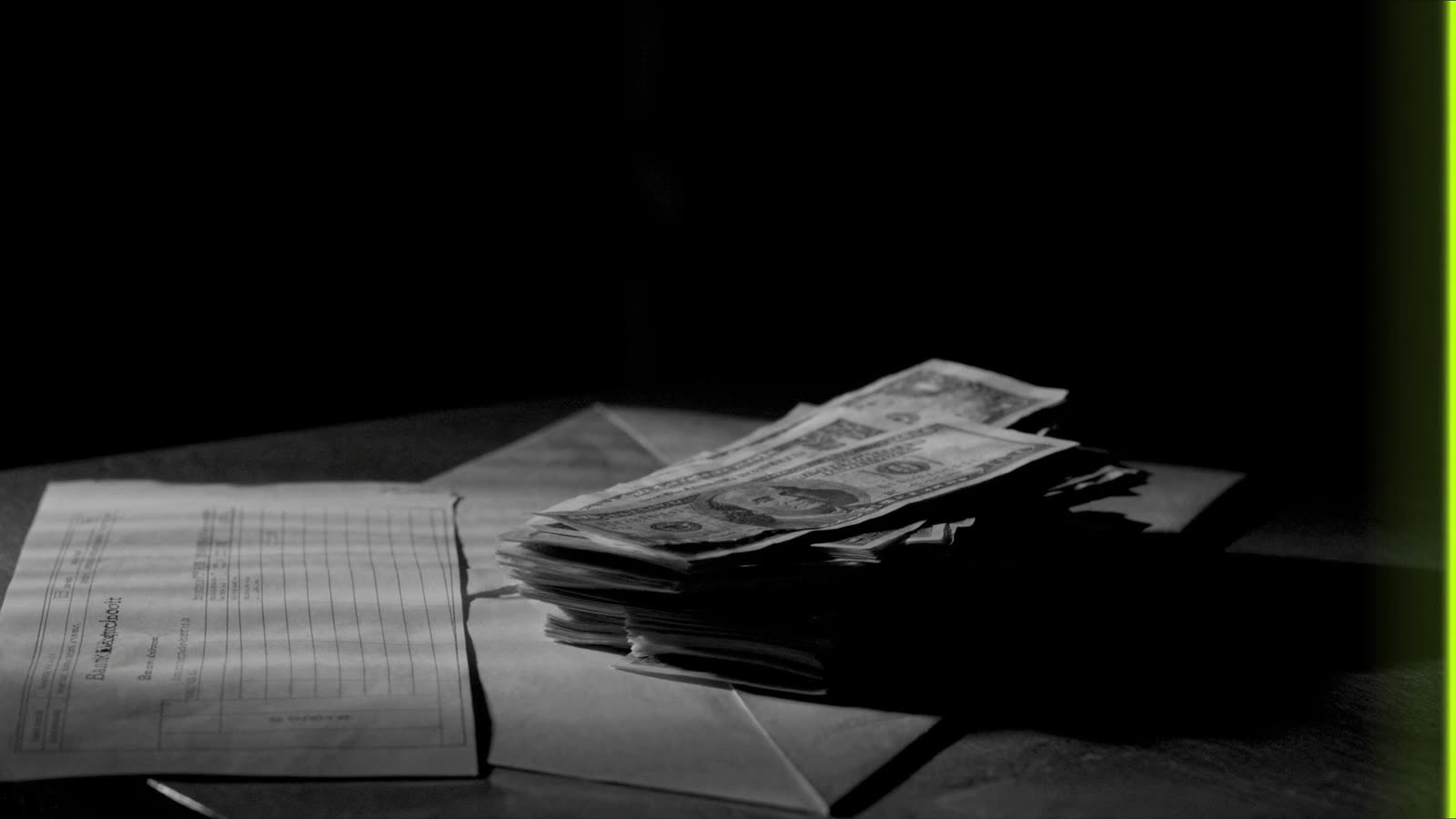 Plik banknotów, koperta i druk wpłaty na drewnianym stole, pasy światła z żaluzji, przy krawędzi kadru zielona poświata
